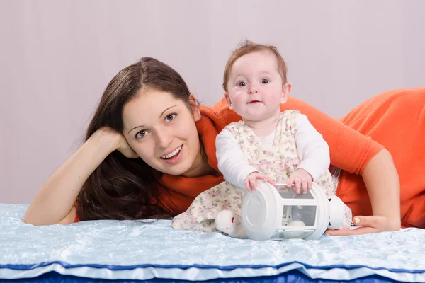 Mamma med en sex månaders dotter spelar på sängen — Stockfoto