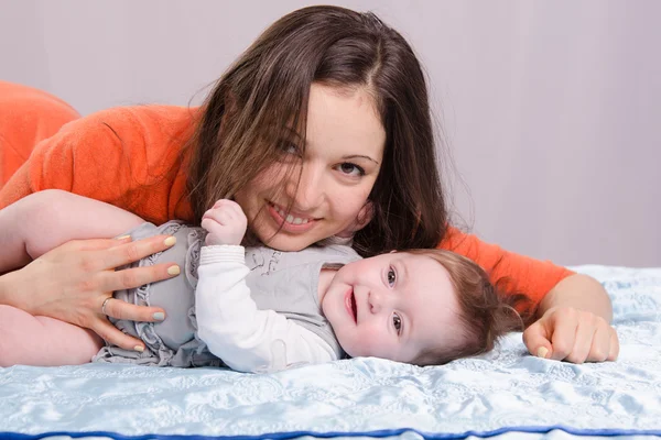 Maman et bébé de sept mois couché sur le canapé amusant — Photo