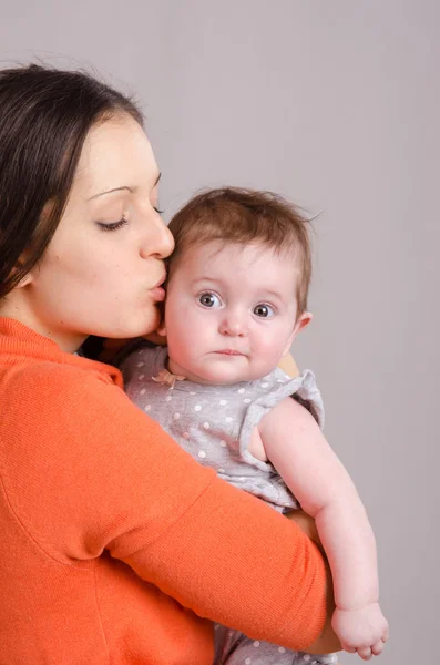 Mãe feliz beijando sua filha de seis meses — Fotografia de Stock