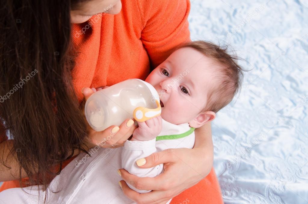 Mum feeds from a bottle six-month baby girl