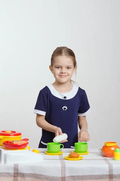 Chica vertiendo leche una taza en la cocina —  Fotos de Stock