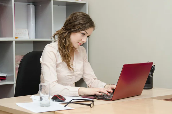 Jeune fille à un ordinateur portable dans le bureau — Photo
