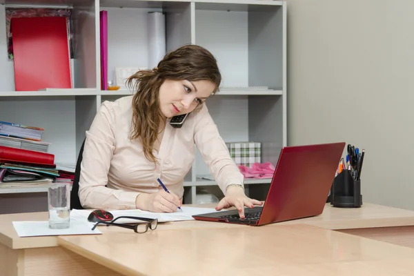 Menina chamando por telefone e trabalhando no laptop — Fotografia de Stock
