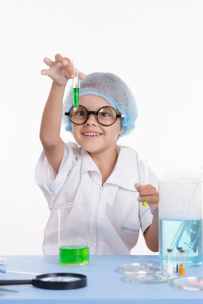 Scientist girl happily looking at test tube with liquid — Stock Photo, Image