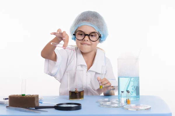 Chemist pours liquid from test tube into a flask — Stock Photo, Image