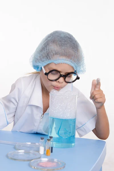 Девушка сдувает фляжку химика с жидкостью — стоковое фото