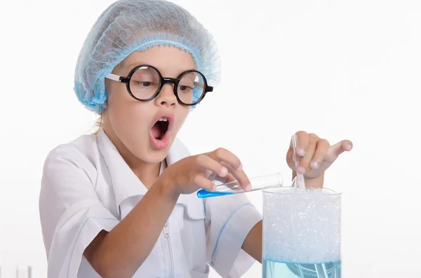Chemiker schüttet blaue Flüssigkeit in Kolben — Stockfoto