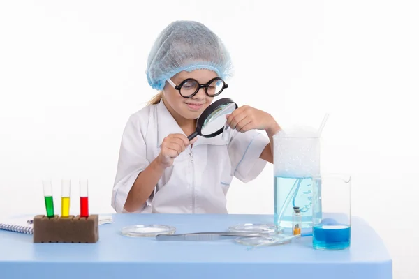 Chemik patrząc przez szkło powiększające na biały proszek — Zdjęcie stockowe