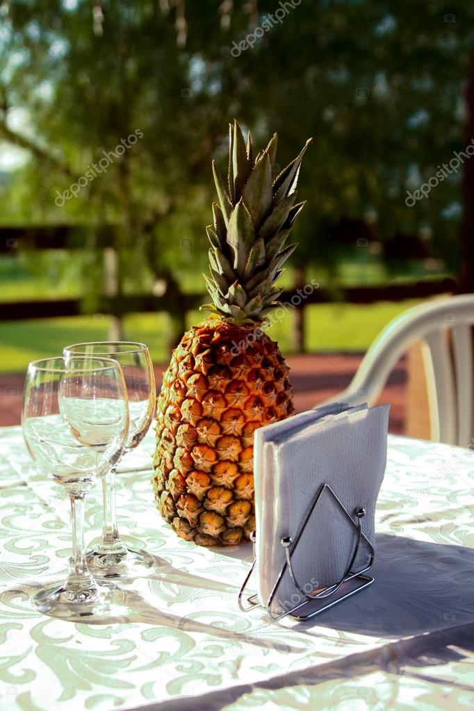 Two wine glasses and pineapple on the served table at sunset