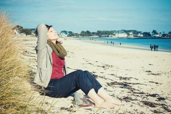 Menina sentada na praia no início da primavera e desfrutar do su Fotos De Bancos De Imagens