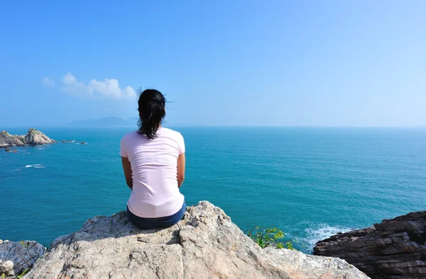 Dos de femme assis sur le rocher de bord de mer — Photo