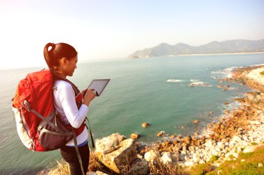 kadın deniz kaya üzerinde durmak ve dijital tablet kullanımı