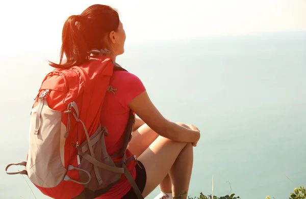 Senderismo mujer relajarse y sentarse junto al mar roca — Foto de Stock