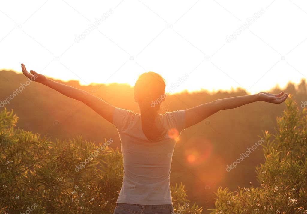 Thankful woman open arms to the sunrise