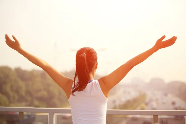 Sporty woman stand at the pedestrian overpass open arms