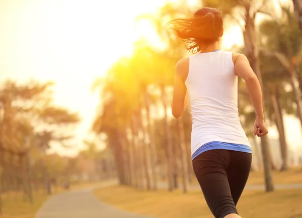 Mujer corriendo por sendero de madera junto al mar — Foto de Stock