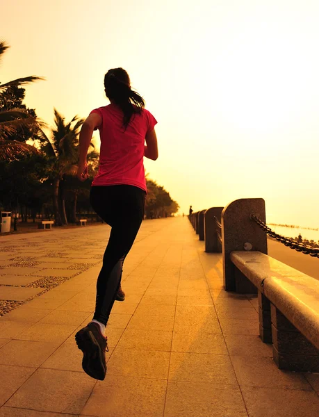Vrouw joggen bij zonsopgang aan zee — Stockfoto