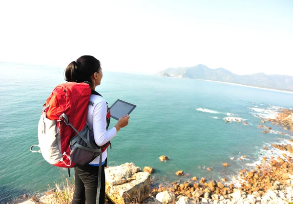 Kadın deniz kaya üzerinde durmak ve dijital tablet kullanımı — Stok fotoğraf