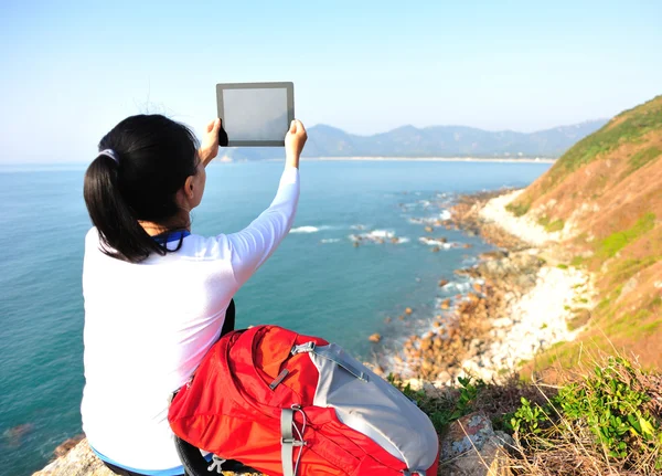 Frau steht auf Felsen am Meer und nutzt digitales Tablet — Stockfoto