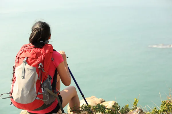 Senderismo mujer relajarse y sentarse junto al mar — Foto de Stock