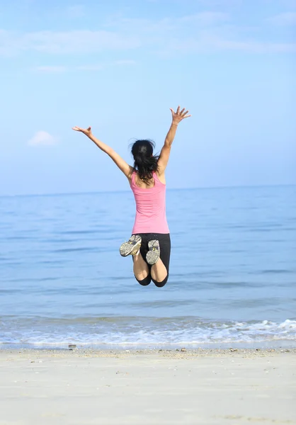 Счастливая женщина, прыгающая на пляже — стоковое фото