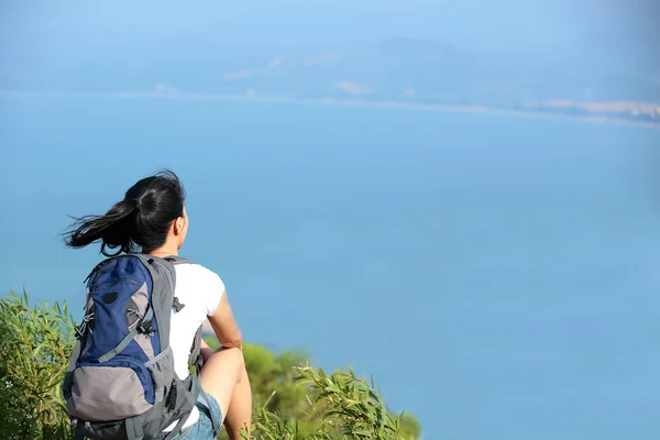 Mujer excursionista sentarse junto al mar —  Fotos de Stock