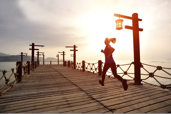 Donna che corre sul sentiero di legno sul mare — Foto Stock