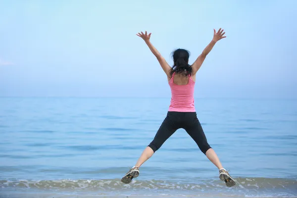 Gelukkig vrouw springen op het strand — Stockfoto