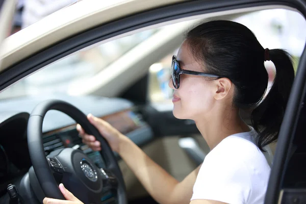 Jovem mulher sorrindo em seu carro — Fotografia de Stock