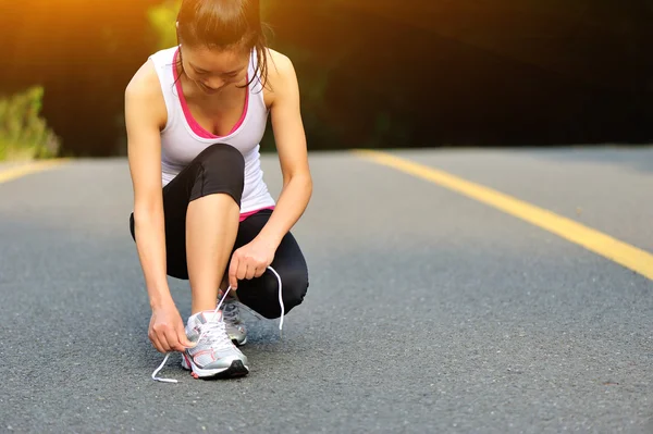 Donna allacciatura lacci delle scarpe su strada — Foto Stock