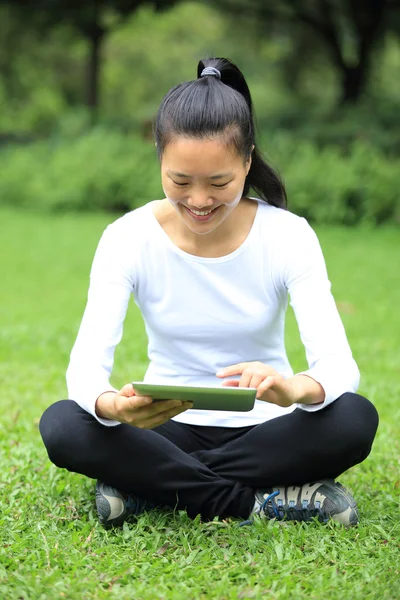 Donna usano tablet digitale sedersi sull'erba — Foto Stock