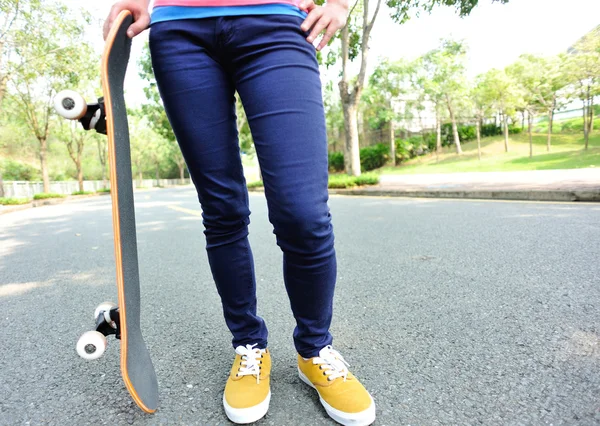 Женщина держит скейтборд на дороге — стоковое фото