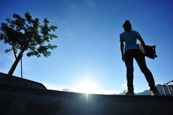 Skateboarding woman at sunrise — Stok fotoğraf