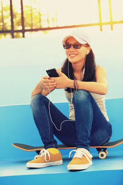 Kvinna skateboardåkare lyssna musik — Stockfoto