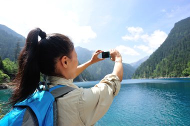Woman tourist taking photo with smart phone clipart