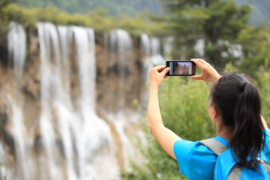 Woman tourist taking photo with smart phone clipart