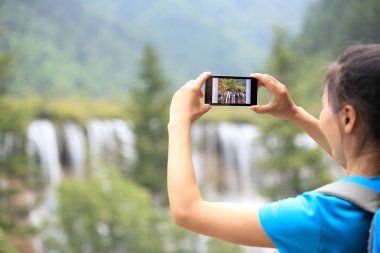 Woman tourist taking photo with smart phone clipart