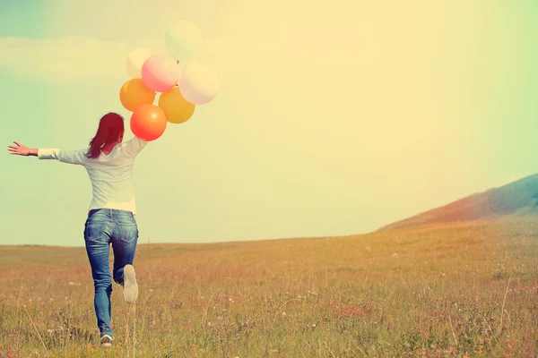 Молода жінка біжить з кольоровими кульками — стокове фото