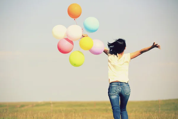 Young woman running with colored balloons — Stock Photo, Image