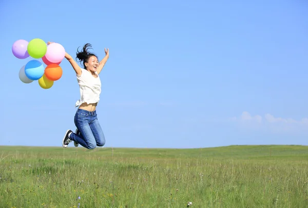 Jeune femme courant avec des ballons colorés — Photo