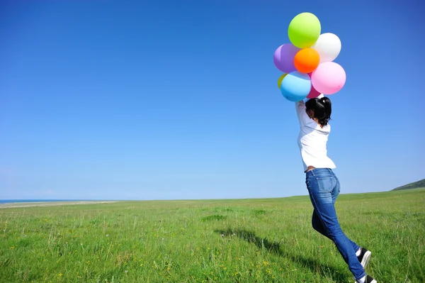 Jeune femme courant avec des ballons colorés — Photo