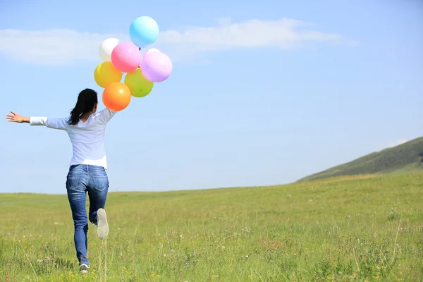 Junge Frau läuft mit bunten Luftballons — Stockfoto