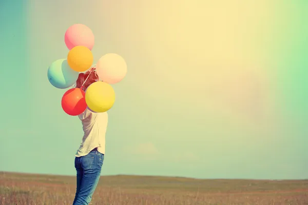 Junge Frau läuft mit bunten Luftballons — Stockfoto
