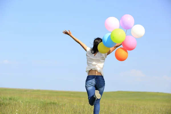 Ung kvinna kör med färgade ballonger — Stockfoto