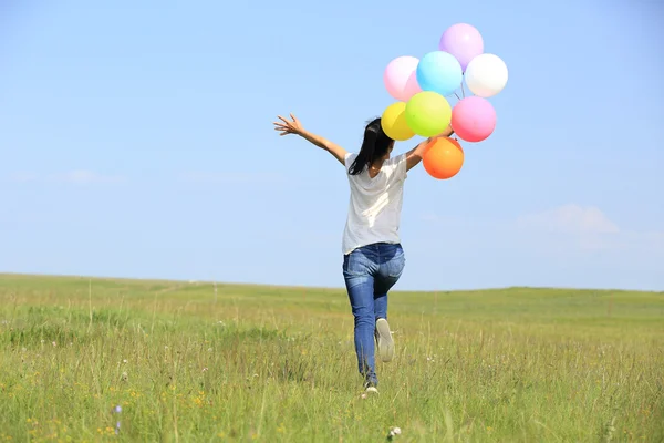 Ung kvinna kör med färgade ballonger — Stockfoto