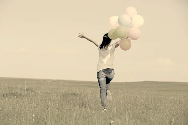 Mujer joven corriendo con globos de colores — Foto de Stock