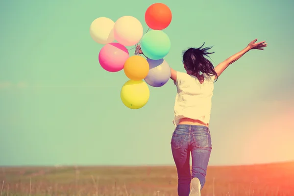 Young woman running with colored balloons — Stock Photo, Image