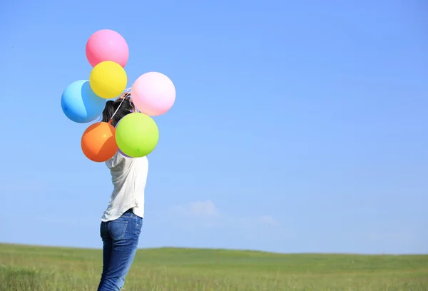 Νεαρή γυναίκα που τρέχει με χρωματιστά μπαλόνια — Φωτογραφία Αρχείου