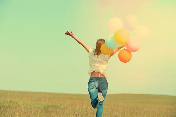 Young woman running with colored balloons — Stock Photo, Image