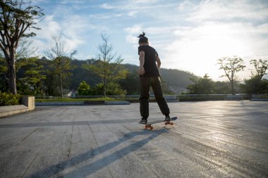 Kaykaycı şehir dışında kaykay yapıyor.